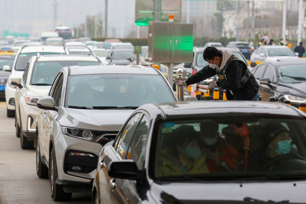   Một nhân viên y tế kiểm tra thân nhiệt người dân ngồi trong xe đi qua trạm thu phí tại thành phố Vũ Hán. Ảnh: Reuters