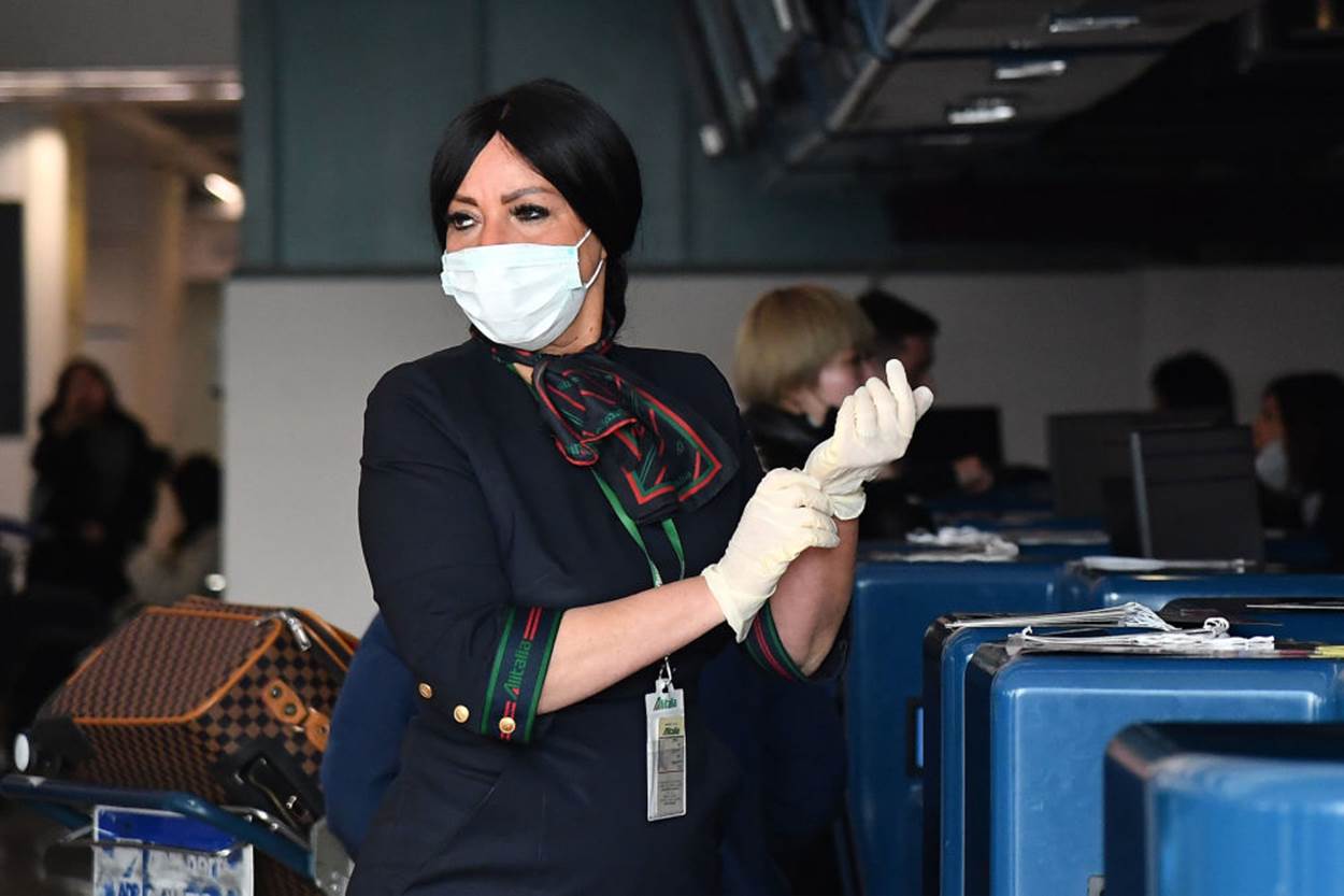  Nhân viên sân bay Fiumicio, Rome, Italy đeo găng tay và khẩu trang y tế để làm thủ tục cho hành khách của hãng China Southern Airlines bay về Vũ Hán, Trung Quốc. Ảnh: Reuters