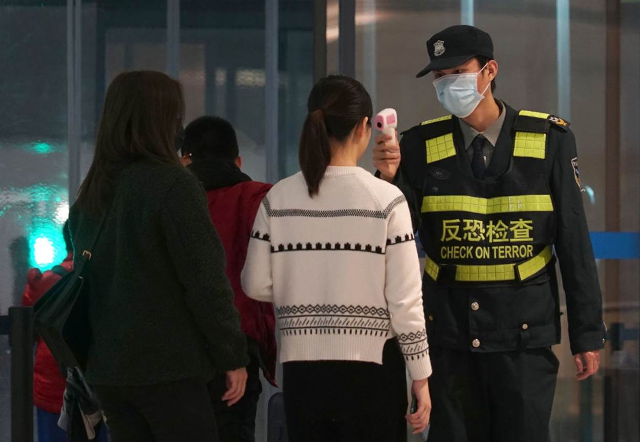  Nhân viên sân bay dùng máy đo nhiệt độ để kiểm tra hành khách rời khỏi sân bay Wuhan Tianhe tại thành phố Vũ Hán. Ảnh: Reuters