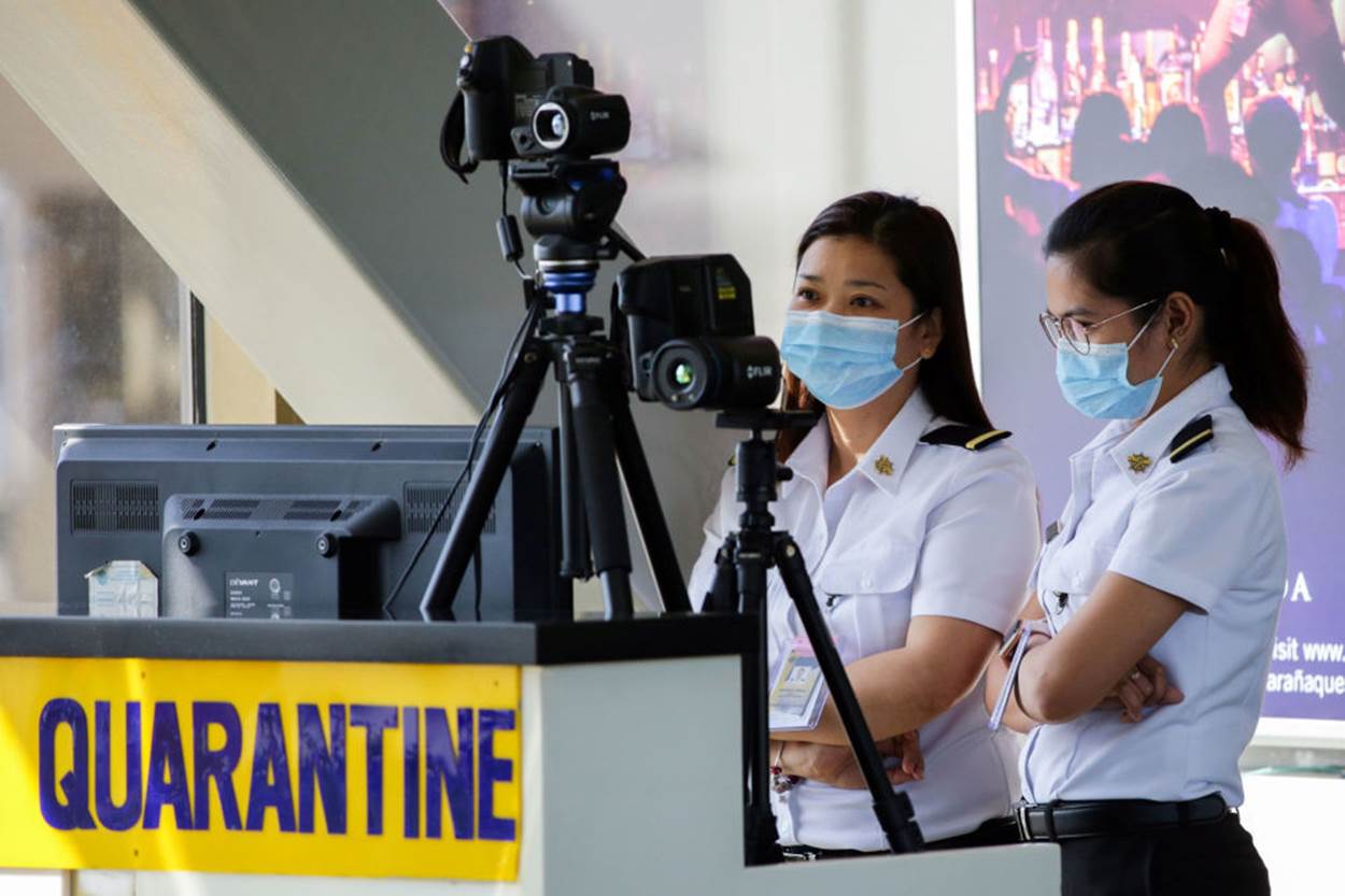 Nhân viên sân bay Ninoy Aquino tại Pasay, Philippines giám sát máy quét thân nhiệt. Ảnh: Reuters