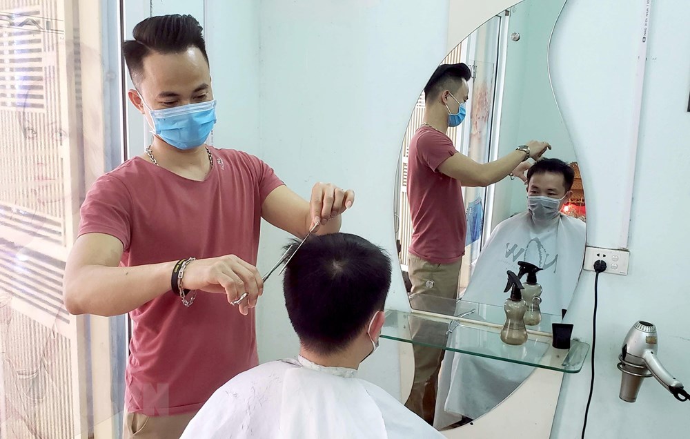  Đeo khẩu trang khi cắt tóc để phòng, chống dịch COVID-19.(Ảnh: Hoàng Hùng/TTXVN)
