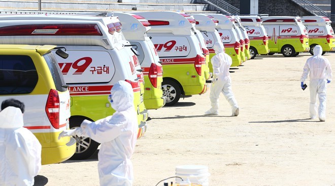 Các nhân viên y tế và xe cấp cứu sẵn sàng đưa bệnh nhân Covid-19 đến bệnh viện ở thành phố Daegu. (Ảnh Reuters)
