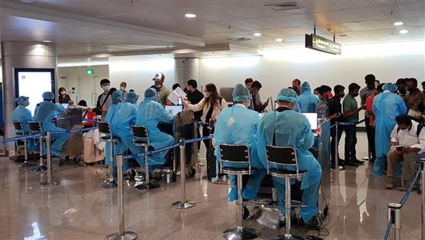 Nhân viên Trung tâm Kiểm dịch y tế quốc tế hướng dẫn hành khách thực hiện tờ khai y tế trước khi làm thủ tục nhập cảnh tại sân bay Tân Sơn Nhất Thành phố Hồ Chí Minh. (Ảnh: TTXVN phát)