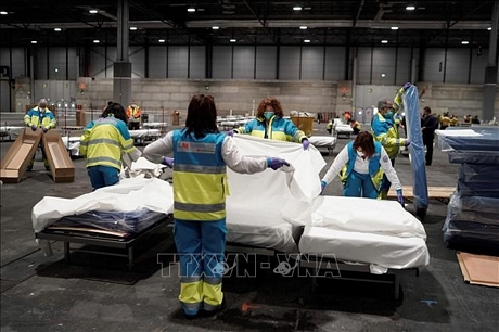 Nhân viên y tế chuẩn bị giường cho bệnh nhân tại bệnh viện dã chiến ở Madrid, Tây Ban Nha, ngày 22/3. Ảnh:THX/TTXVN