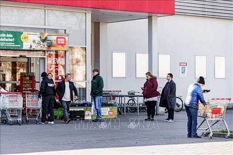 Người dân xếp hàng bên ngoài một siêu thị ở Berlin, Đức ngày 23/2. Ảnh: THX/TTXVN