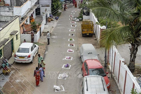 Người dân dùng túi đặt vào ô để xếp hàng trong khi chờ nhận gạo miễn phí cho người dân bị ảnh hưởng bởi dịch COVID-19 tại Hyderabad, Ấn Độ, ngày 1/4/2020. Ảnh: AFP/TTXVN