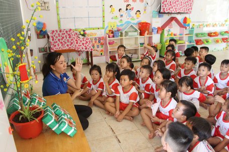 Chị Võ Thị Kim Anh làm nhành mai, bánh chưng, dưa hấu giả để kể câu chuyện về tết cho các em bé trên đảo.