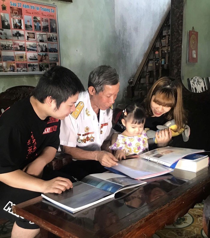 Cựu chiến binh Lê Xuân Phát kể cho con cháu về những ngày đi GPTS và kỷ niệm khi ông còn công tác. Ảnh Cẩm Lai.