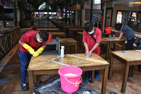 Nhân viên tẩy vết băng dính dán trên bàn để chuẩn bị mở cửa lại nhà hàng ở Lau Pa Sat, Singapore, ngày 15/6/2020. Ảnh: Straits Times 