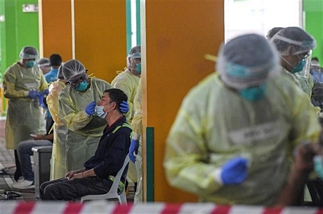  Nhân viên y tế lấy mẫu xét nghiệm COVID-19 tại Singapore. Ảnh: AFP/TTXVN