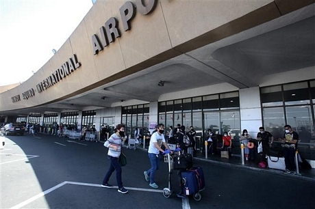 Hành khách xếp hàng bên ngoài sân bay quốc tế Manila, Philippines, ngày 19/3/2020. Ảnh: AFP/ TTXVN