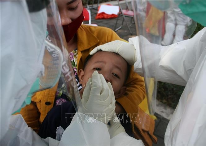 Nhân viên y tế lấy mẫu dịch xét nghiệm COVID-19 cho trẻ em tại Surabaya, Indonesia ngày 20/7. Ảnh: THX/TTXVN