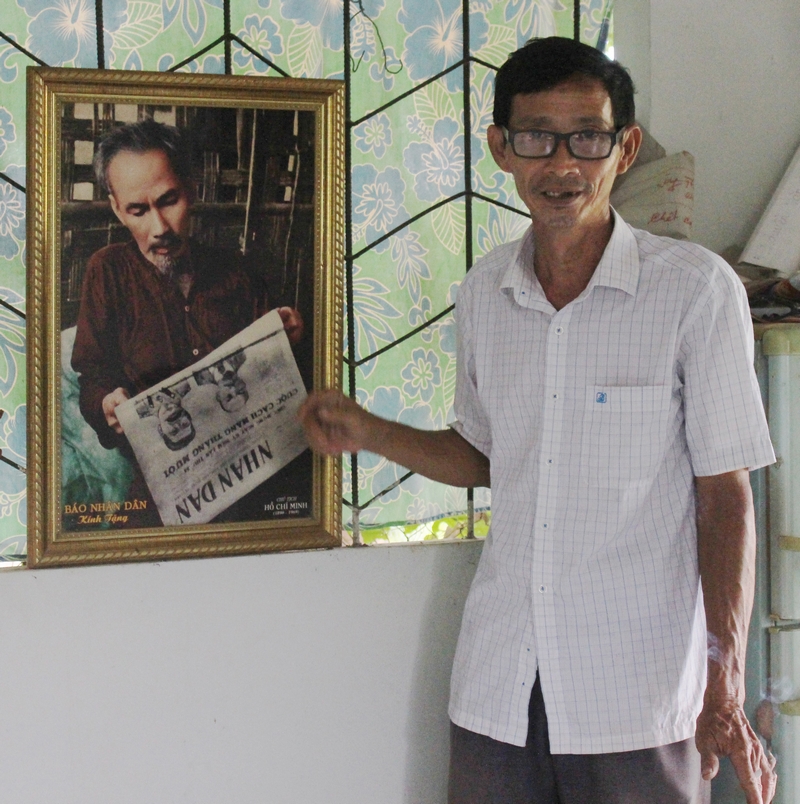 Ông Hoa Sĩ Hiền bên bức ảnh Bác Hồ đọc báo.