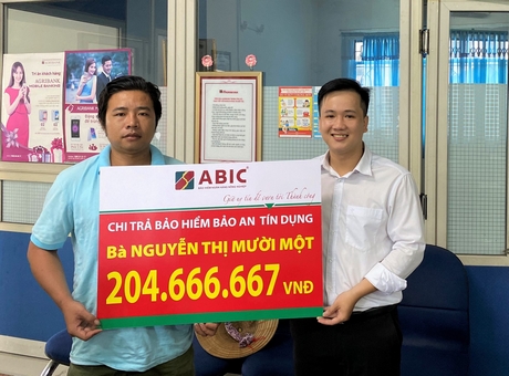 Ông Đoàn Chí Linh- đại diện Agribank huyện Tam Bình (bên phải) trao biểu trưng cho gia đình khách hàng.