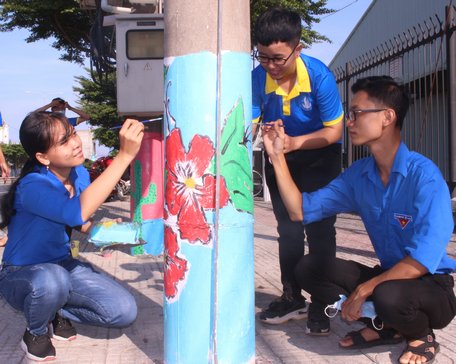 Nhóm sinh viên Trường ĐH Sư phạm kỹ thuật Vĩnh Long vẽ hoa cho cột điện.