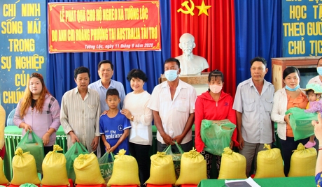 Ông Lưu Thành Công và bà Huỳnh Kim Nguyên (đứng thứ 3 từ trái qua) trao quà cho các hộ có hoàn cảnh khó khăn ở xã Tường Lộc