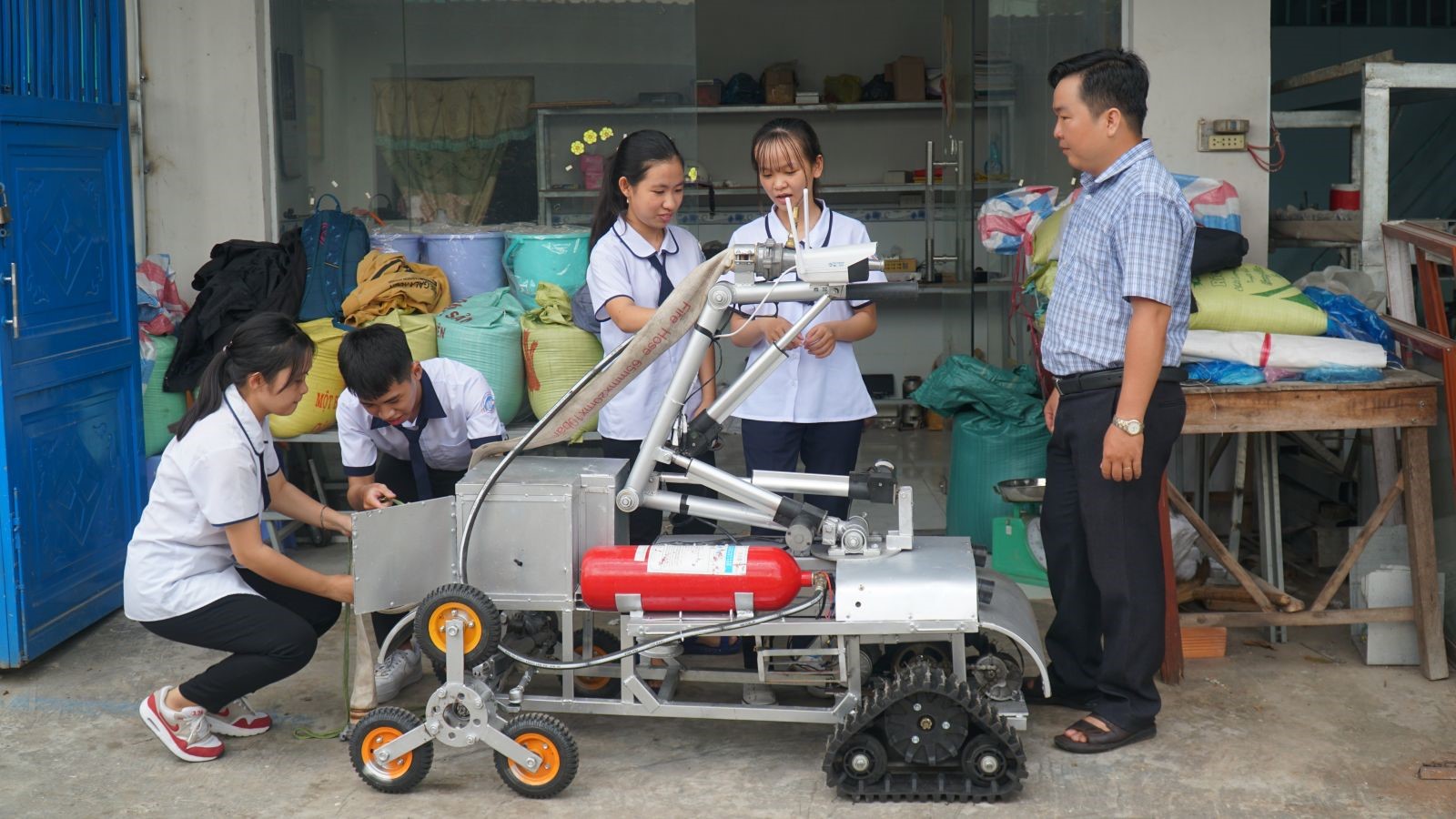 Thầy Nguyễn Phúc Thịnh và các học sinh bên robot chữa cháy.
