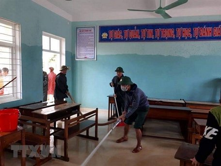 Lực lượng bộ đội cùng người dân tham gia dọn vệ sinh trường THCS Cảnh Hóa, huyện Quảng Trạch (Quảng Bình) để đón học sinh trở lại. (Ảnh: Đức Thọ/TTXVN)