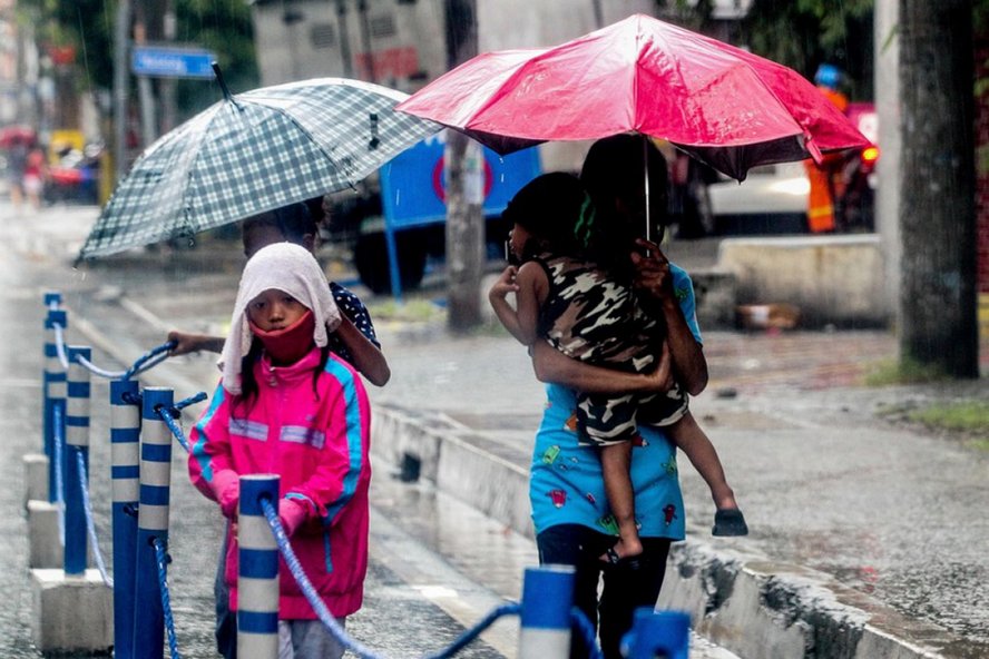 Một người phụ nữ cùng con nhỏ đang nhanh chóng về nhà khi bão Molave gây mưa lớn ở Manila ngày 25/10. Ảnh: Tân Hoa xã.