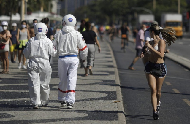  Hai người này mặc đồ bảo hộ lấy cảm hứng từ đồ của các phi hành gia, họ mặc trong một cuộc đi dạo bộ bên bờ biển ở Brazil giữa mùa hè.