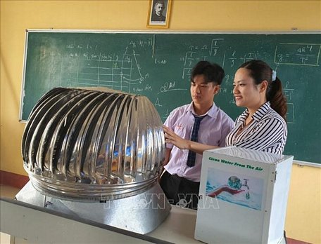 Trần Hữu Tỉ và cô giáo hướng dẫn Vũ Thị Thúy Hằng, giáo viên bộ môn Vật Lý nghiên cứu cải tiến mô hình máy tạo ra nước sạch từ năng lượng điện gió. Ảnh: Ánh Tuyết/TTXVN