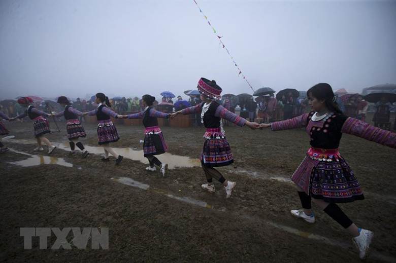  Các chàng trai, cô gái Mông cùng du khách nắm tay nhau nhảy múa theo tiếng khèn xung quanh cây nêu mặc cho trời mưa và gió lạnh. (Ảnh: Trọng Đạt/TTXVN)