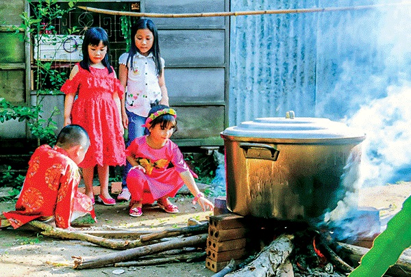 Bếp quê và cúng Ông Táo ghi dấu ấn sâu đậm trong tâm thức dân gian của người Nam Bộ. Trong ảnh: Các em nhỏ bên bếp lửa nấu bánh tét chiều 30 Tết. Ảnh: DUY KHÔI