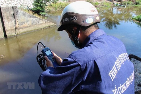 Công nhân vận hành cống kiểm tra độ mặn tại cống Kênh Lầu, xã Hỏa Tiến. (Ảnh: Hồng Thái/TTXVN)