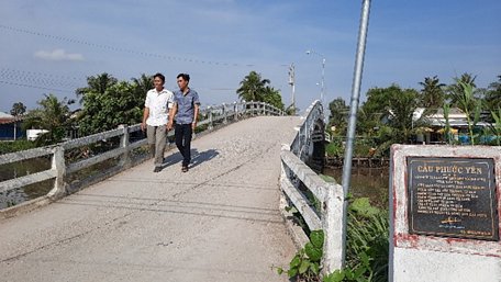 Ông Tuấn (bên trái) trên cây cầu mà ông đóng góp 60 triệu đồng xây dựng.