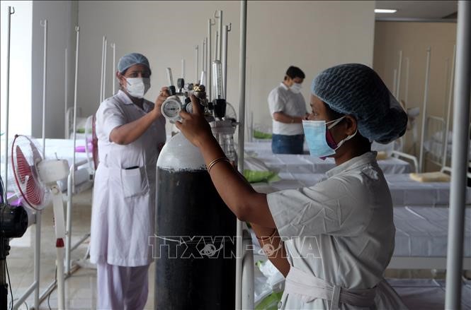 Nhân viên y tế chuẩn bị bình oxy cho bệnh nhân COVID-19 tại Kolkata, Ấn Độ. Ảnh: THX/TTXVN
