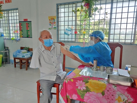 Tiêm vắc xin phòng COVID-19 giúp phòng ngừa và giảm biến chứng nặng của COVID-19. Trong ảnh: Ông Phạm Minh Tiến (81 tuổi, thương binh 2/4, thị trấn Cái Nhum- Mang Thít) khi tiêm vắc xin.
