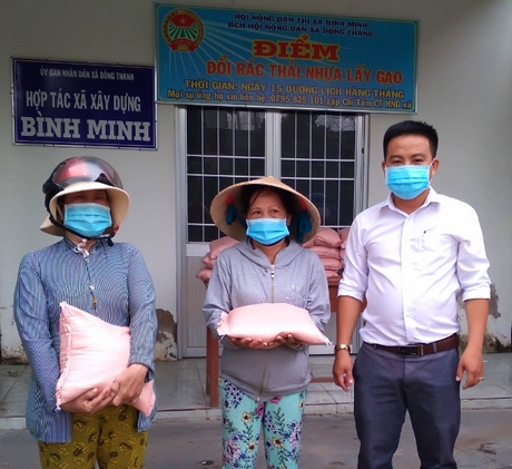 Ông Nguyễn Chí Tâm (phải) trao gạo hỗ trợ cho hộ dân đem rác thải nhựa đến đổi và hộ phụ trách nhặt rác.