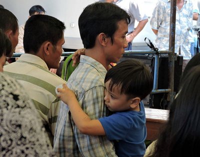 Anh Trần Quốc Thanh thẫn thờ tại phiên tòa, trong khi bé Luân may mắn thoát chết sau tai nạn, cứ ôm chặt lấy cha - Ảnh: Thúy Hằng