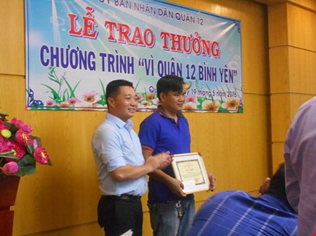 Ông Lê Trương Hải Hiếu- Chủ tịch UBND Quận 12 trao bằng khen cùng số tiền thưởng 2 triệu đồng cho anh Hồ Hiếu Tâm. ẢNH: THANH TUYỀN