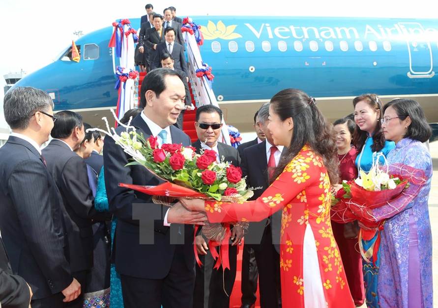 Đại diện Nhà nước Lào cùng cán bộ nhân viên Đại sứ quán Việt Nam và đông đảo kiều bào đón Chủ tịch nước Trần Đại Quang và phu nhân tại sân bay quốc tế Wattay. (Ảnh: Nhan Sáng/TTXVN)