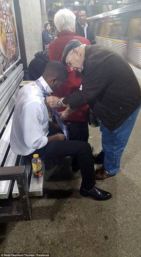 Một người đàn ông giúp đỡ nam thanh niên thắt cà vạt.