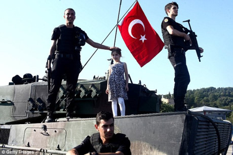 Bé gái Thổ Nhĩ Kỳ đứng cạnh nhân viên an ninh trên một chiếc xe tăng thu lại từ lực lượng đảo chính đã bị dập tắt. (ảnh: Getty).