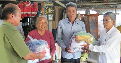 Ông Huỳnh Minh Việt (bìa phải) trao quà cho hộ nghèo.