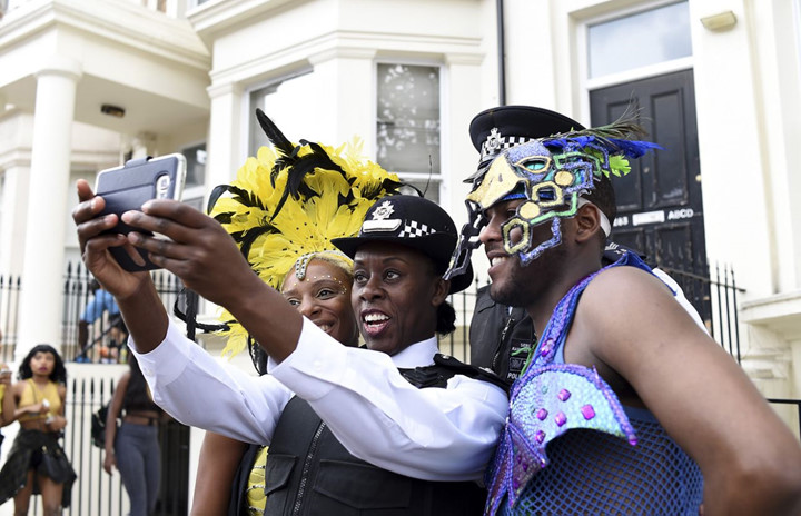 Khoảnh khắc một cảnh sát chụp ảnh cùng với 2 người dân tham gia lễ hội. (ảnh: Getty).
