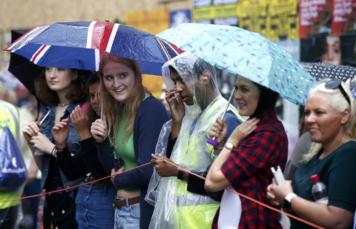 Bất chấp mưa gió, nhiều người dân mặc áo mưa, che ô để tham gia lễ hội. (ảnh: Reuters).