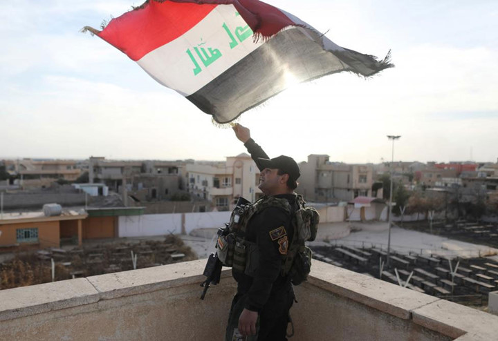 Một chiến binh lực lượng đặc nhiệm Iraq vẫy cờ Iraq trên nóc một ngôi nhà thờ đã bị IS phá hủy, ở khu vực Bartella, phía đông Mosul.