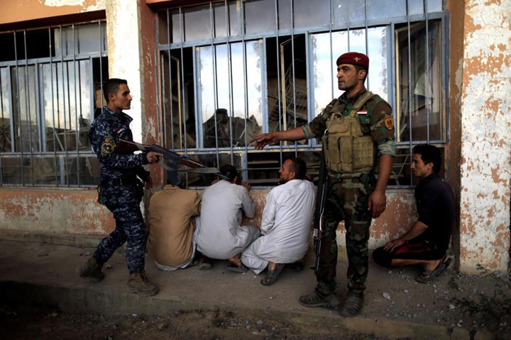 Chiến binh lực lượng đặc nhiệm Iraq canh giữ những người nghi là phiến quân IS, ở khu vực Qayyara, phía nam thành phố Mosul.