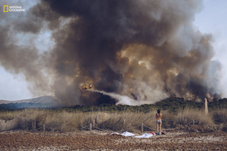 Một thiếu nữ mặc bikini đứng bên bờ biển Son Serra, đảo Mallorca, chứng kiến cảnh dập tắt đám lửa gần đó. (Nguồn: businessinsider.com)