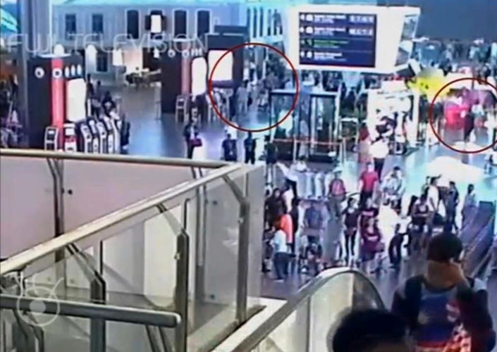 Người phụ nữ trong bộ trang phục áo thun trắng và quần jean (vòng tròn bên phải) bỏ đi sau khi thực hiện vụ tấn công nhằm vào ông Kim Jong-nam (vòng tròn bên trái). (Ảnh: FUJITV/via Reuters TV)