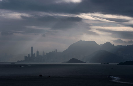 Một con phà (dưới bên phải) di chuyển về phía đảo Hong Kong (Trung Quốc) khi ánh sáng mặt trời chiếu xuyên qua các đám mây. Ảnh: AFP.