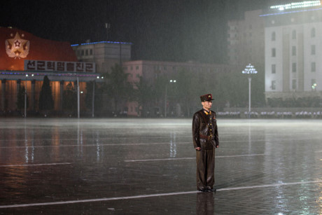 Một người lính Triều Tiên đứng dưới trời mưa trên quảng trường Kim Nhật Thành ở thủ đô Bình Nhưỡng vào tối 10/10/2015. Ảnh: AFP.