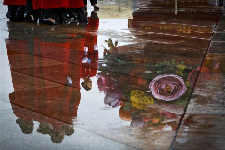 Bóng của các nữ tiếp tân in trên một vũng nước ở khu vực quảng trường Thiên An Môn. Ảnh: AP
