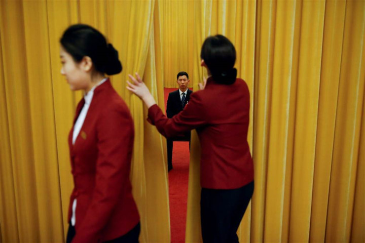 Một nhân viên an ninh tập trung làm nhiệm vụ trong lúc các nhân viên lễ tân chỉnh lại tấm rèm. Ảnh:  Reuters.