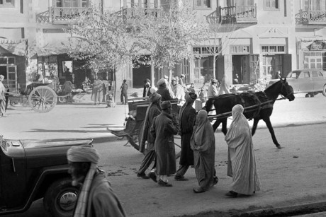 Phụ nữ Afghanistan mặc trang phục burqa truyền thống và đi dép Ba Tư, tản bộ bên các nam giới, ô tô và xe ngựa ở đường phố thủ đô Kabul vào năm 1951.