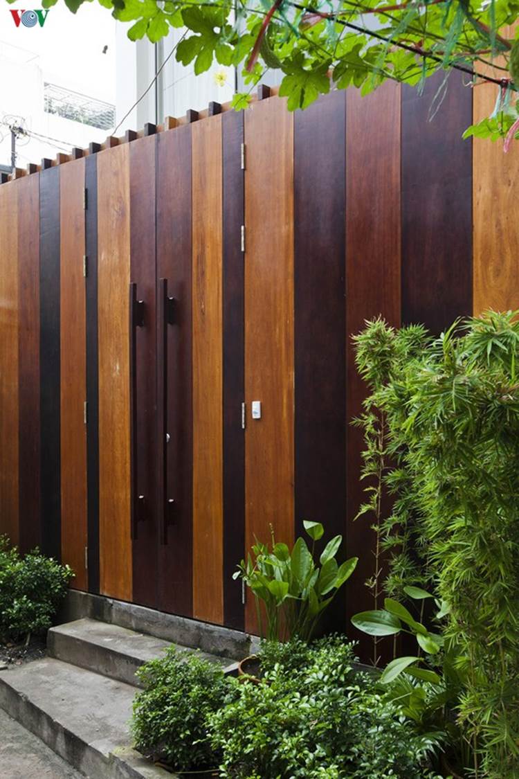 Kiến trúc sư đã có một lời giải hợp lý cho bài toán khó, đáp ứng được những nhu cầu của chủ nhà. Vì ngõ nhỏ nên để kín đáo, cổng sử dụng mảng đặc, nhưng vẫn thân thiện nhờ chất liệu gỗ và những chậu cây xanh phía trước.